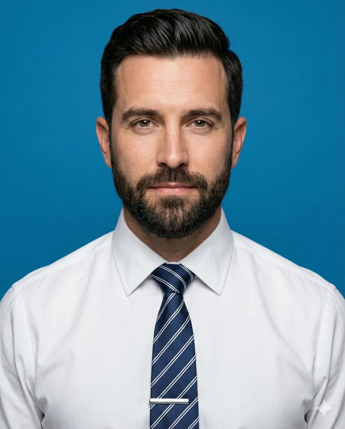 Professional Man Blue Backdrop AI Photo Editing Prompt. AI generated studio portrait of a bearded man wearing a white dress shirt and striped tie against a solid blue background.