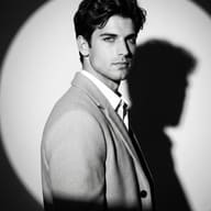 Black and White Man in Spotlight AI Photo Editing Prompt. AI generated high-fashion studio portrait of a man wearing a tailored coat casting a sharp shadow under dramatic circular lighting.