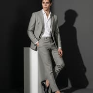 Man in Grey Suit AI Photo Editing Prompt. AI generated fashion portrait of a stylish young man in a tailored grey suit and black loafers leaning on a white pedestal.