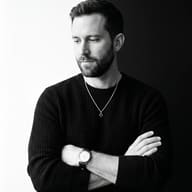 Man Monochrome Portrait AI Photo Editing Prompt. AI generated minimalist studio portrait of a man with crossed arms wearing a textured sweater and wristwatch against a split background.